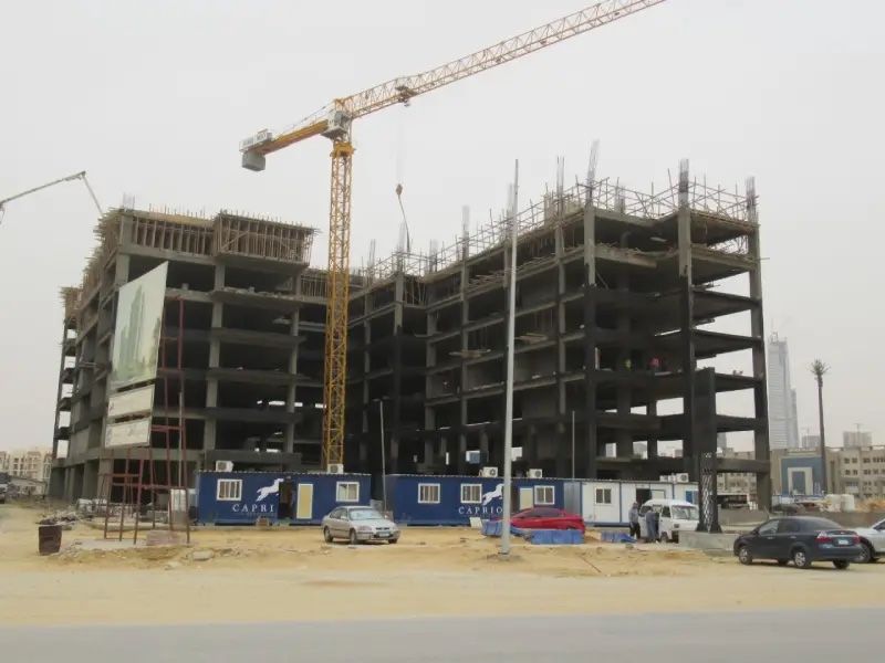 The concrete frames of both LINX Tower blocks with a tower crane above and Capriole site cabins in front