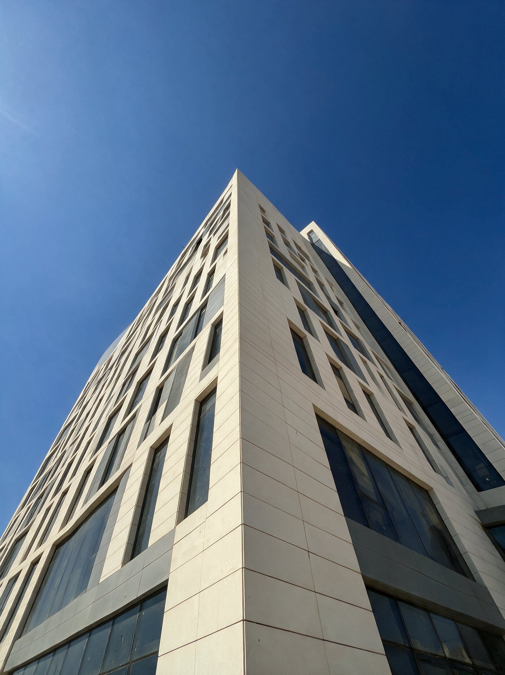 Looking up the corner of LINX Tower against a clear blue sky