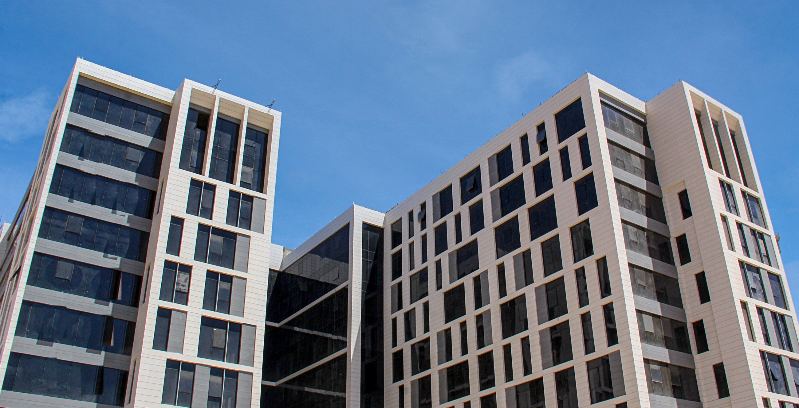 The two office blocks of LINX Tower joined by a glass link, photographed against a blue sky